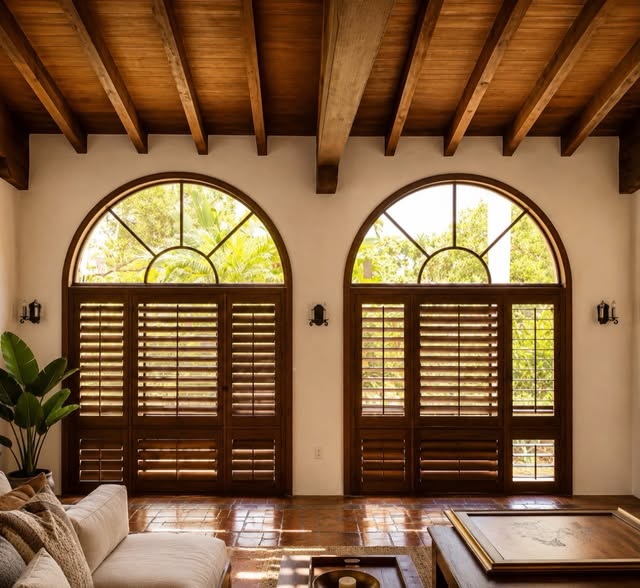 Architectural woodwork framing arched windows, shutters and ceiling beams in a living space