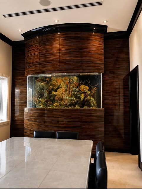 Custom dark-toned wall millwork surrounding a built-in aquarium and dining area